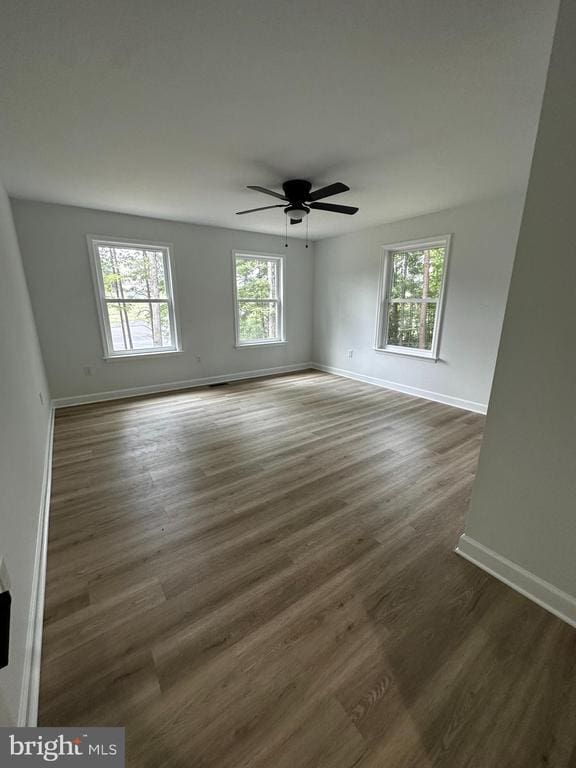 empty room with dark hardwood / wood-style floors and ceiling fan