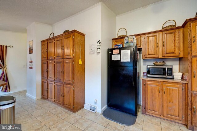 kitchen featuring crown molding, freestanding refrigerator, and stainless steel microwave
