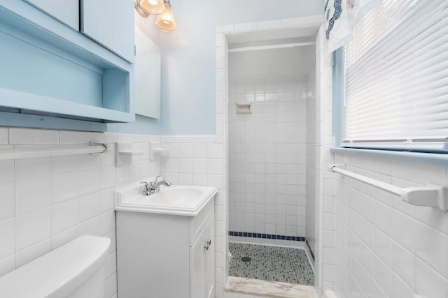 full bathroom with vanity, a wainscoted wall, a stall shower, tile walls, and toilet