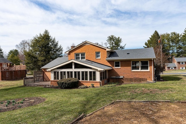 rear view of property with a wooden deck, brick siding, a chimney, and a lawn