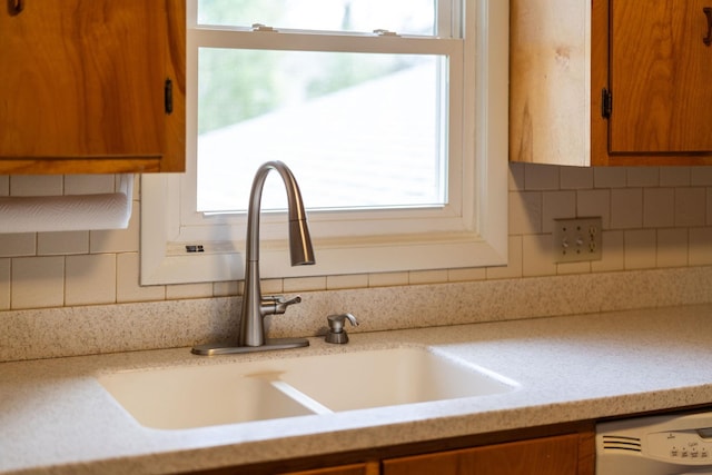 details with brown cabinets, a sink, light countertops, decorative backsplash, and dishwasher