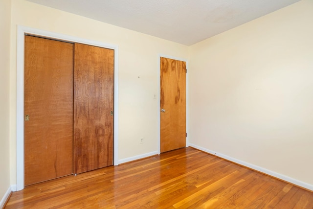 unfurnished bedroom featuring a closet, baseboards, and wood finished floors