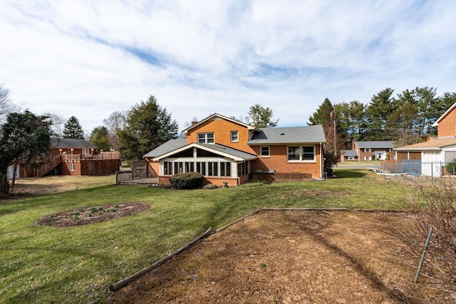 back of house featuring brick siding, a lawn, and a deck