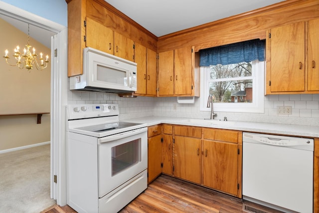 kitchen with white appliances, light countertops, light wood-style floors, and a sink