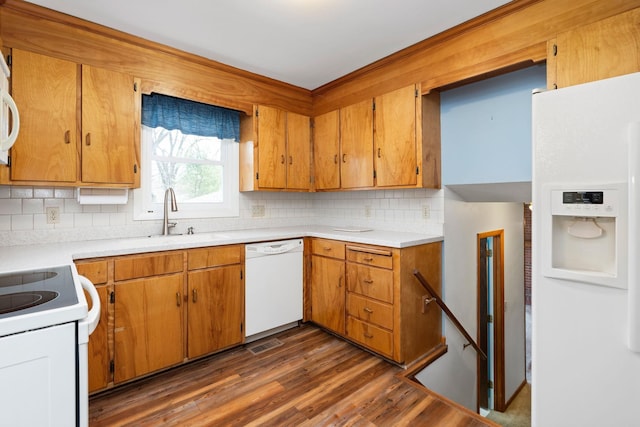 kitchen featuring backsplash, light countertops, dark wood-style floors, white appliances, and a sink