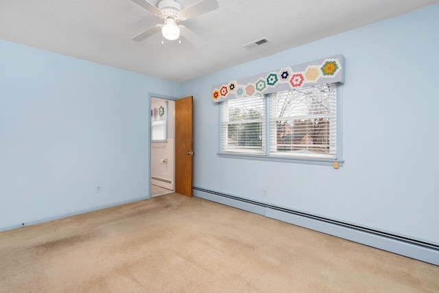 carpeted spare room featuring a textured ceiling, visible vents, baseboard heating, and ceiling fan