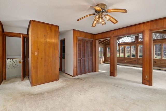 interior space featuring ceiling fan, crown molding, wood walls, and a baseboard radiator