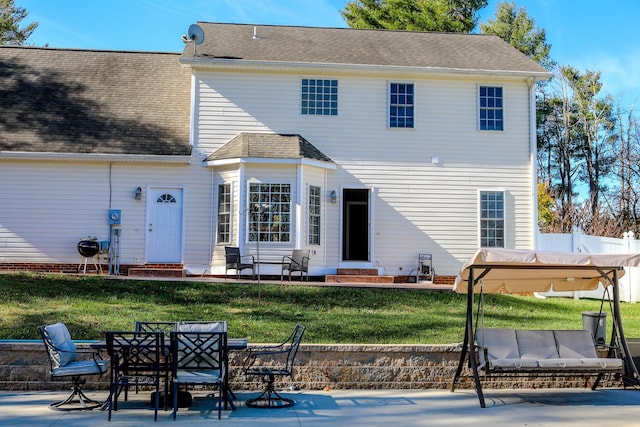 rear view of house featuring a patio, a shingled roof, a lawn, entry steps, and fence