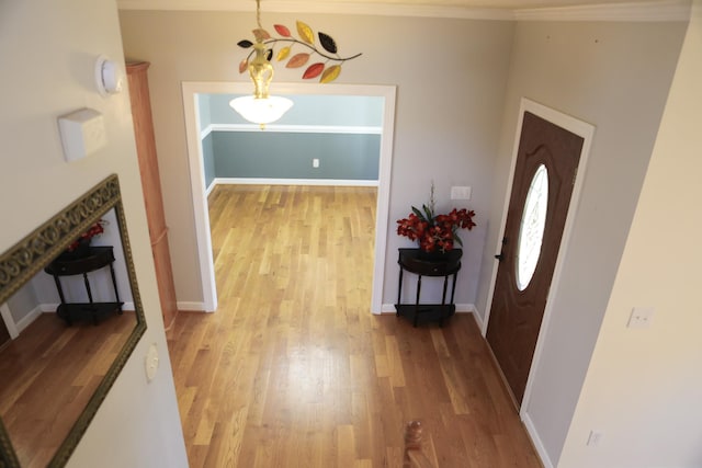 foyer featuring light wood-style flooring, baseboards, and crown molding