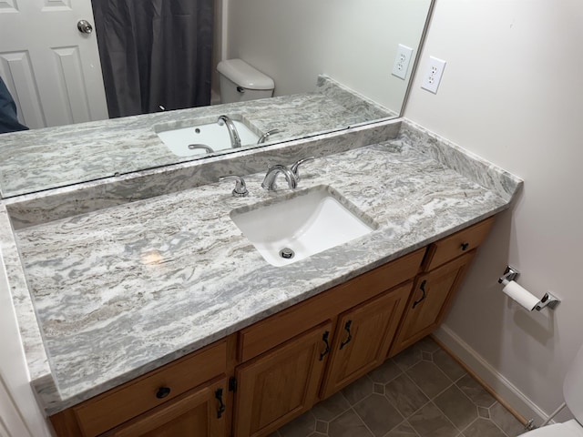 bathroom with baseboards, vanity, toilet, and tile patterned floors