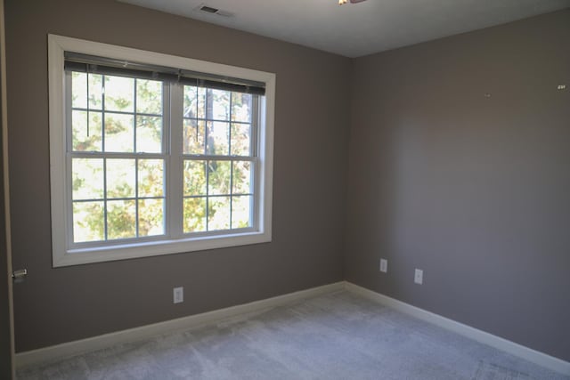 empty room featuring light carpet, visible vents, and baseboards