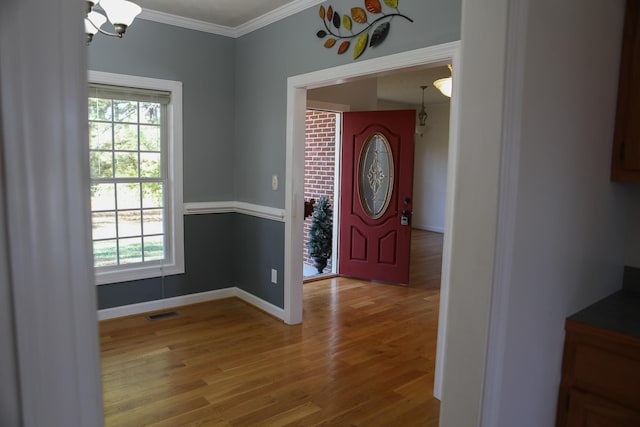 entryway with visible vents, crown molding, baseboards, and wood finished floors