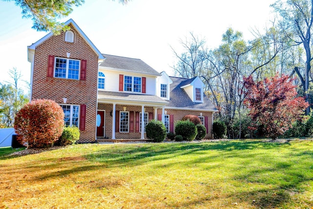 traditional-style home with covered porch, brick siding, and a front lawn