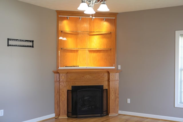 unfurnished living room with a chandelier, light wood finished floors, a fireplace, and baseboards