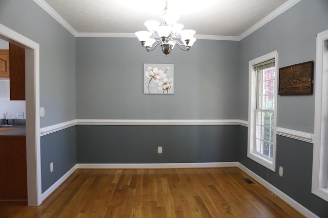 unfurnished dining area featuring ornamental molding, wood finished floors, visible vents, and baseboards