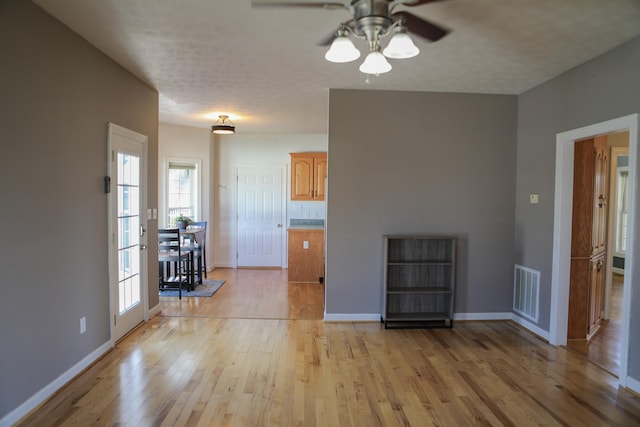 unfurnished living room with light wood-style flooring, visible vents, and baseboards