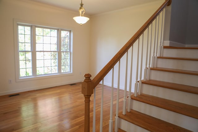 staircase with baseboards, crown molding, visible vents, and wood finished floors