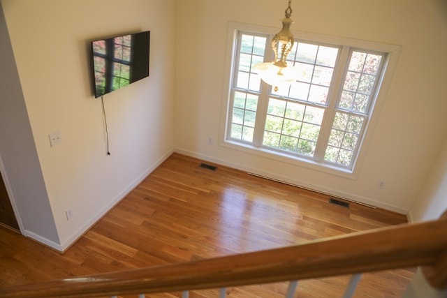 empty room with a wealth of natural light, visible vents, and wood finished floors