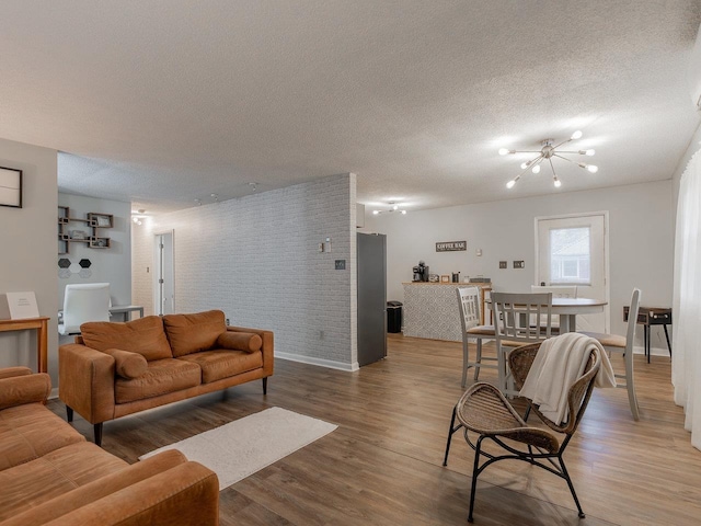 living room with hardwood / wood-style flooring, a textured ceiling, and brick wall