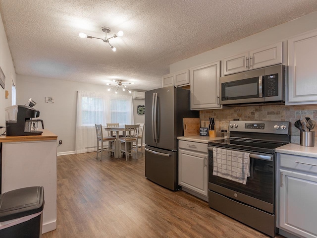 kitchen with appliances with stainless steel finishes, white cabinets, and light wood-type flooring