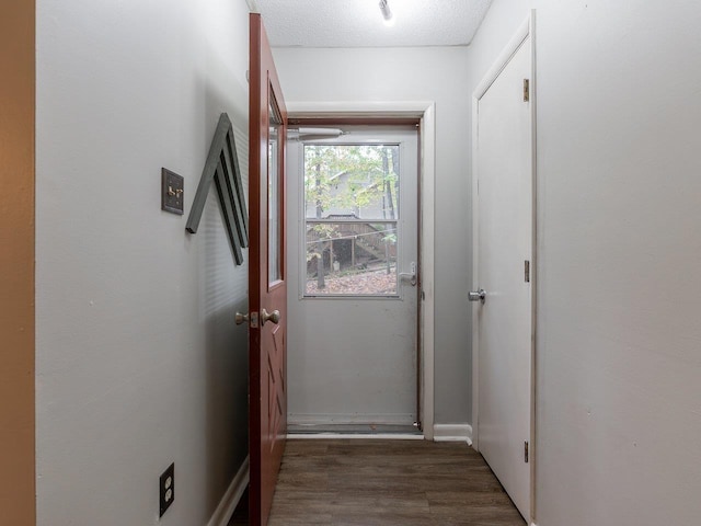 doorway to outside featuring a textured ceiling and dark hardwood / wood-style flooring