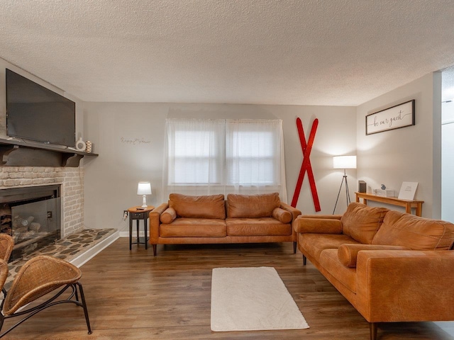 living room with dark wood-type flooring, a brick fireplace, and a textured ceiling