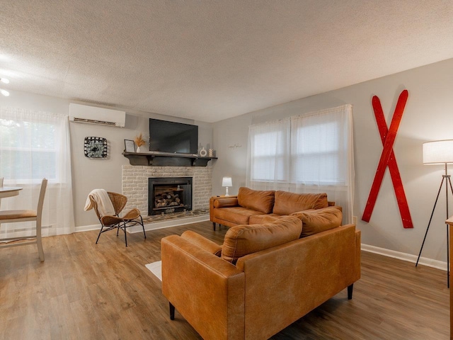 living room with wood-type flooring, an AC wall unit, a textured ceiling, and a fireplace