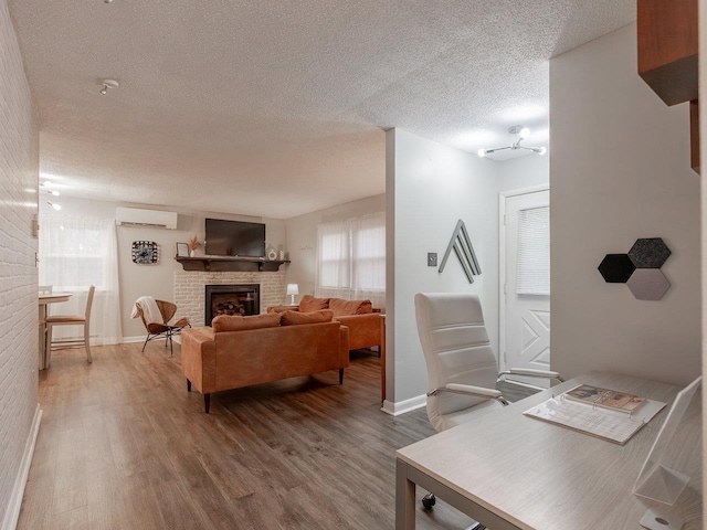 living room featuring a fireplace, hardwood / wood-style floors, a textured ceiling, and an AC wall unit