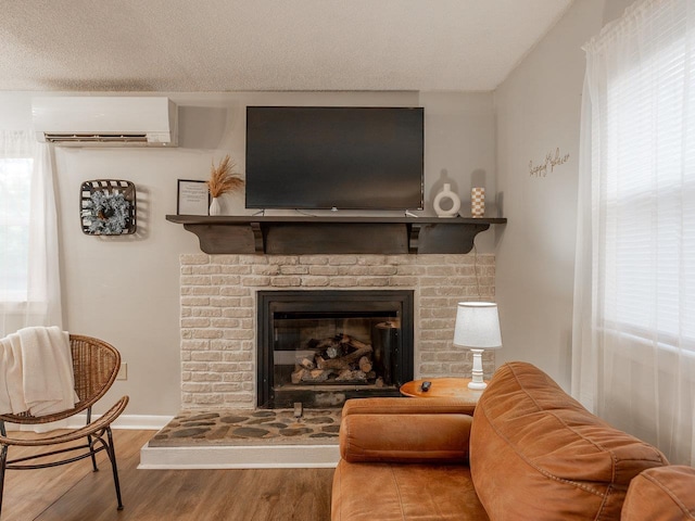 living room featuring a fireplace, hardwood / wood-style floors, a textured ceiling, and an AC wall unit