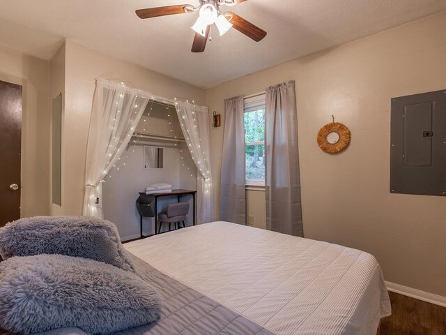 bedroom featuring hardwood / wood-style flooring, ceiling fan, and electric panel