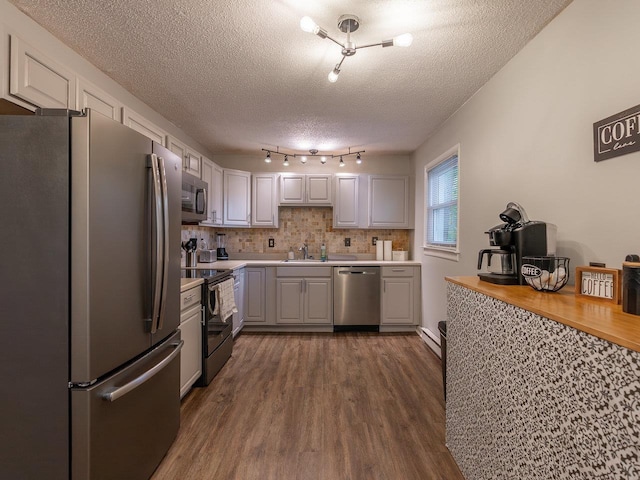 kitchen featuring white cabinetry, a textured ceiling, appliances with stainless steel finishes, dark hardwood / wood-style flooring, and backsplash