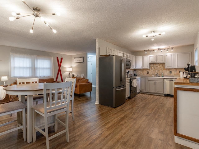 kitchen with white cabinetry, dark hardwood / wood-style flooring, decorative backsplash, stainless steel appliances, and a textured ceiling