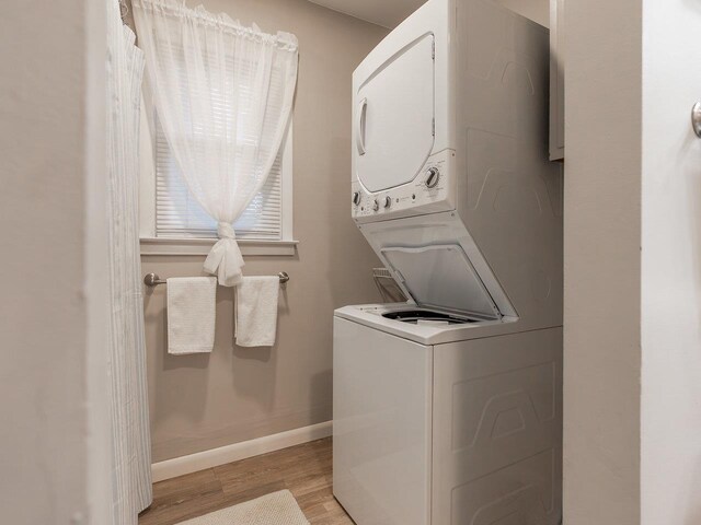 clothes washing area with stacked washer and dryer and light wood-type flooring