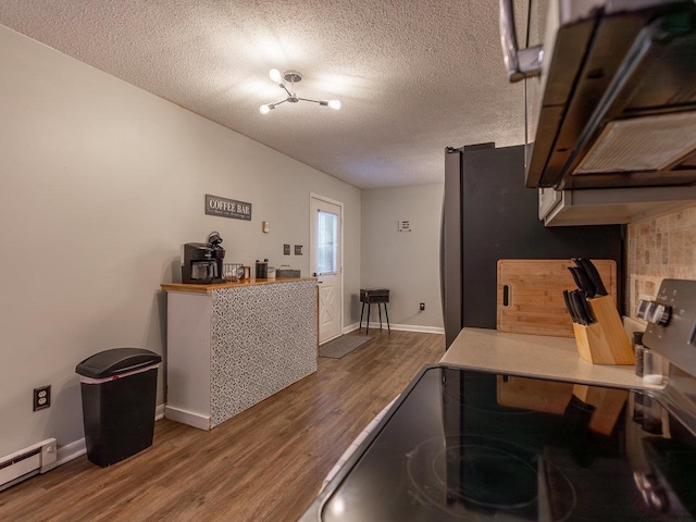 kitchen featuring a textured ceiling, dark hardwood / wood-style floors, electric stove, range hood, and a baseboard heating unit