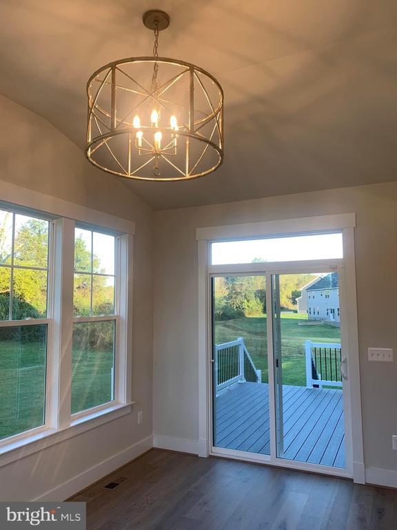 doorway to outside with visible vents, baseboards, vaulted ceiling, wood finished floors, and a notable chandelier