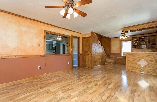 interior space with hardwood / wood-style flooring, wooden walls, ornamental molding, and a textured ceiling