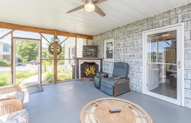 unfurnished sunroom with ceiling fan and exterior fireplace