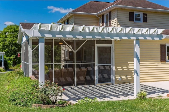 rear view of house with a balcony, a patio, and a sunroom