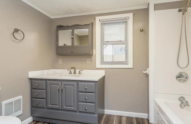 bathroom featuring shower / washtub combination, hardwood / wood-style flooring, vanity, ornamental molding, and a textured ceiling