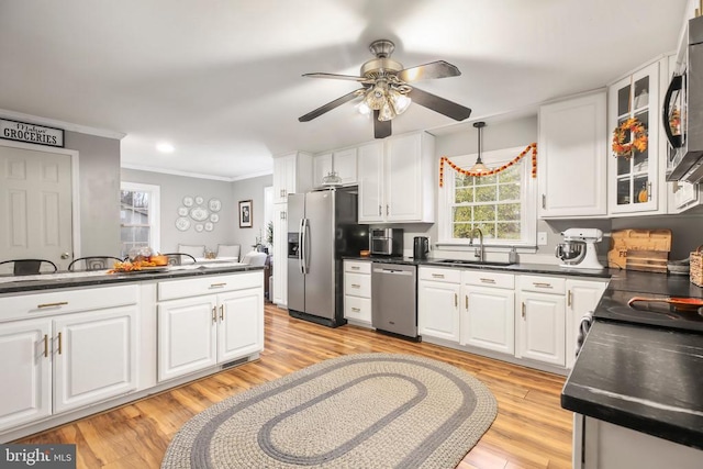 kitchen featuring light wood-type flooring, a sink, dark countertops, stainless steel appliances, and white cabinets