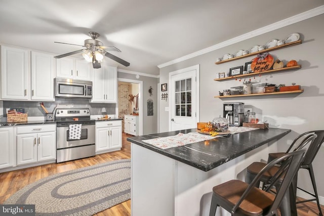 kitchen with backsplash, appliances with stainless steel finishes, a peninsula, white cabinetry, and open shelves