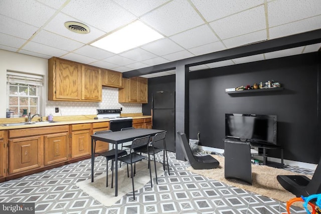 kitchen featuring electric range, visible vents, a sink, freestanding refrigerator, and light countertops