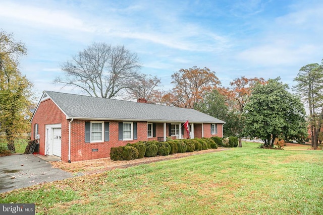 ranch-style home featuring brick siding, an attached garage, a chimney, and a front yard