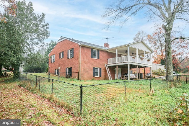 back of house with brick siding, ceiling fan, a chimney, a fenced backyard, and a yard