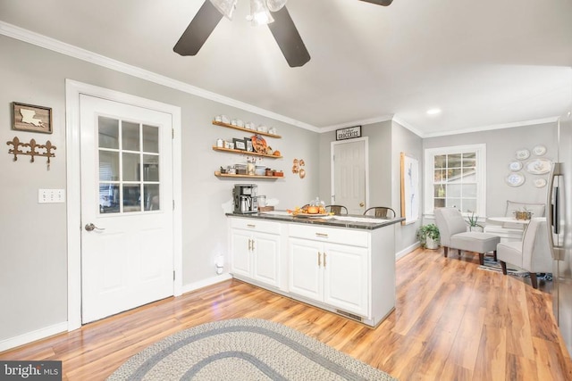 kitchen featuring light wood-style floors, dark countertops, white cabinets, and crown molding