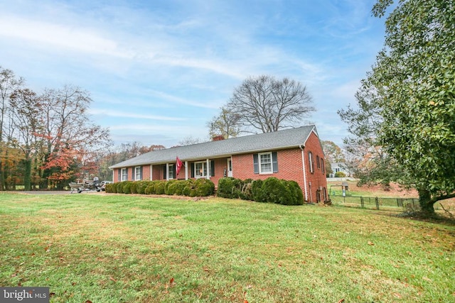 ranch-style house with brick siding, a chimney, a front lawn, and fence