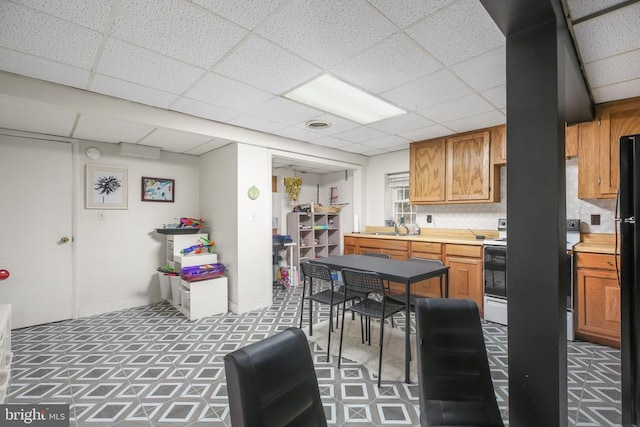 kitchen with visible vents, freestanding refrigerator, a sink, stove, and light countertops