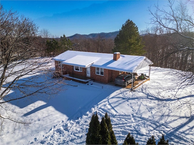 snow covered rear of property with a carport and a mountain view