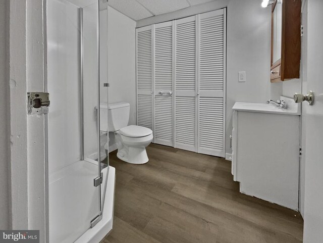 bathroom featuring hardwood / wood-style flooring, vanity, a shower with door, and toilet