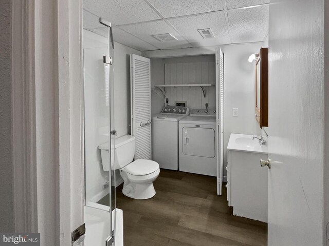 bathroom with hardwood / wood-style flooring, a paneled ceiling, vanity, washing machine and clothes dryer, and toilet